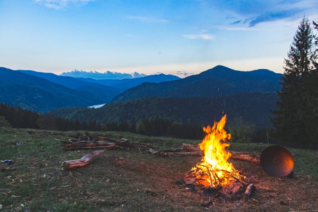 Cozy campfire against a mountain backdrop at twilight in Valea Drăganului, Romania.